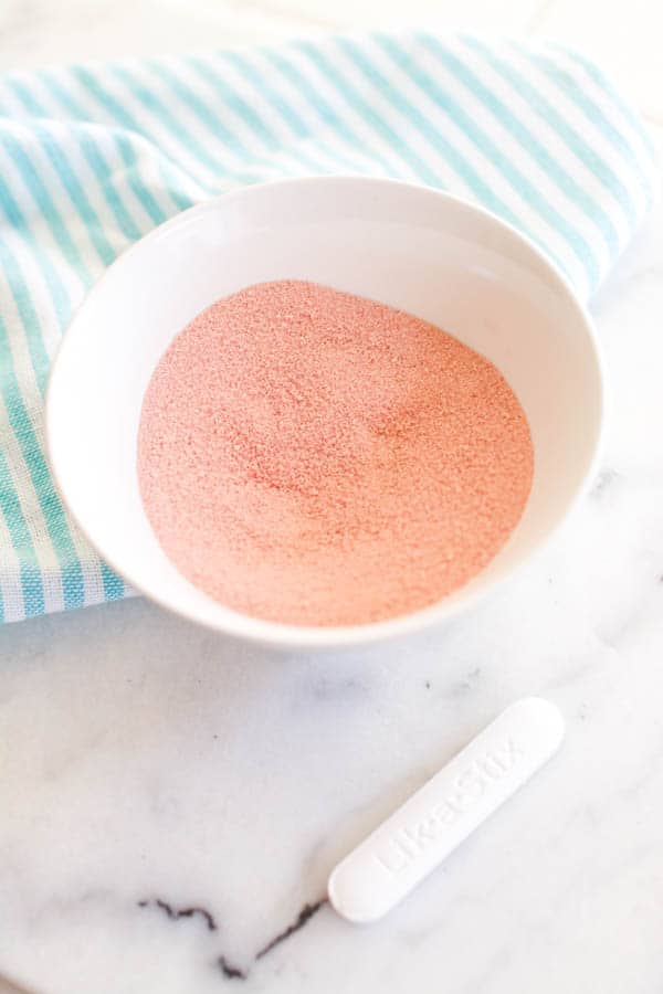 A white bowl with pink candy powder which is a DIY version of Cherry Fun Dip candy.