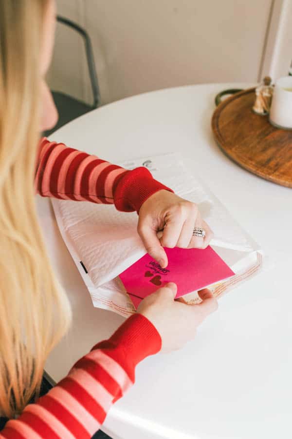 Woman putting a year's worth of greeting cards into a mailing envelope.