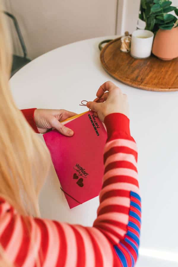 Woman tying twine around greeting cards to make a long distance best friend gift.