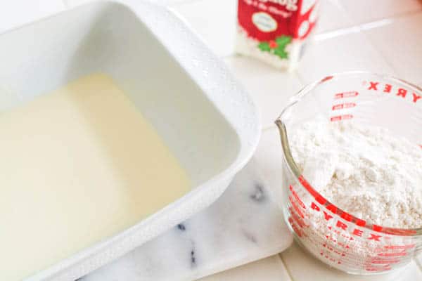 A pan with eggnog and measuring cup of cake mix.