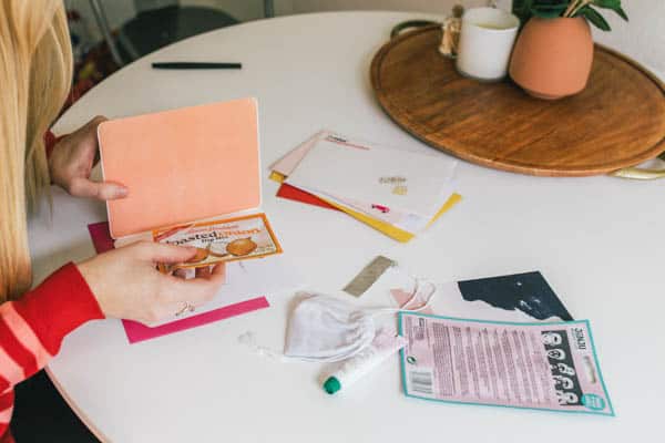 Woman adding a small gift to a greeting card.