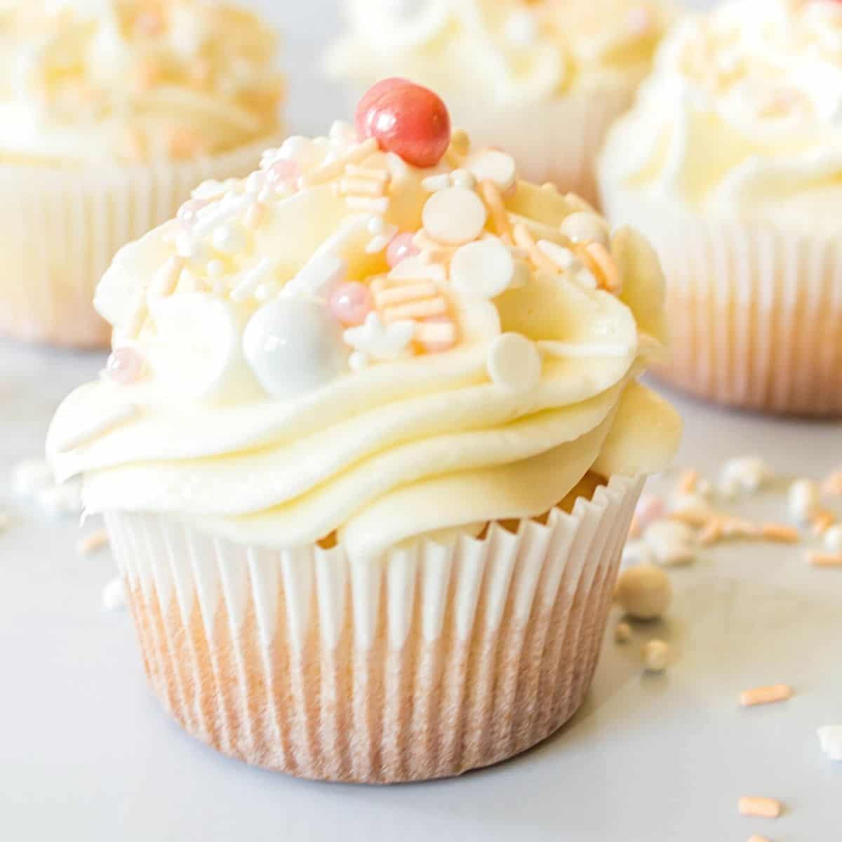 Close up of Prosecco buttercream topped prosecco cupcakes with sprinkles on a table.