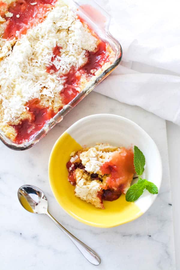 A yellow and white dessert bowl with a portion of cherry dump cake made in the microwave. 