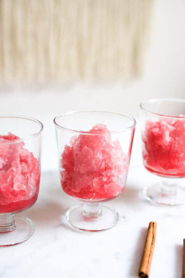 Festive Cranberry Slush cocktail in footed glasses on a table. 