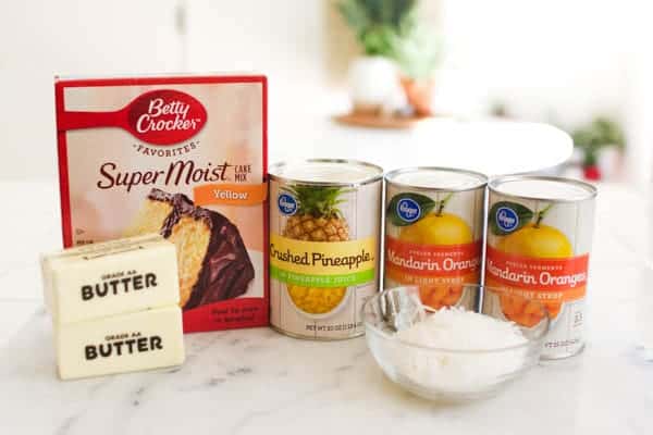 Ingredients on a counter to make an orange dump cake with crushed pineapple and coconut.