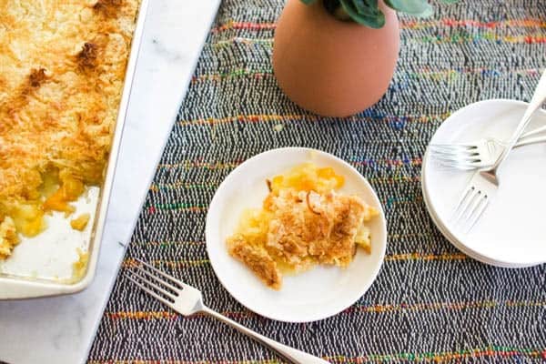 Dessert plate with a serving of pineapple mandarin orange dump cake next to a baking dish full of it.