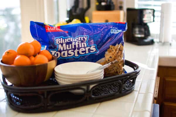 Tray with bowls and spoons next to a bag of cereal on a counter.