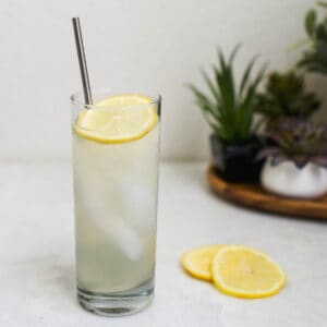 Cocktail in a tall glass with lemon garnish.