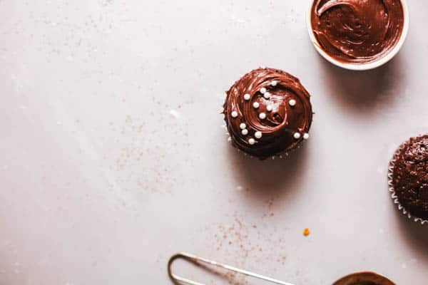 Chocolate cupcake on a table with white round sprinkles. 