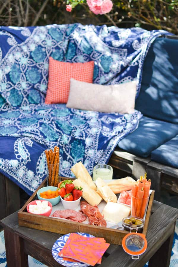 Food on a picnic table in front of an outdoor sofa.