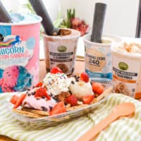 Ice cream nachos on a table next to different flavors of ice cream.