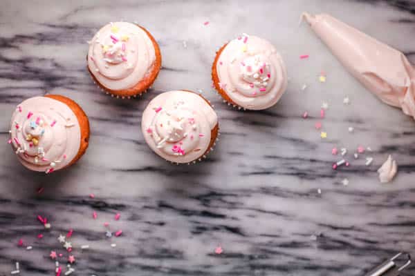 Overhead view of pink cupcakes with sprinkles. 