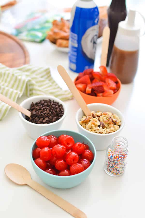 Small bowls holding ice cream sundae toppings on a table. 