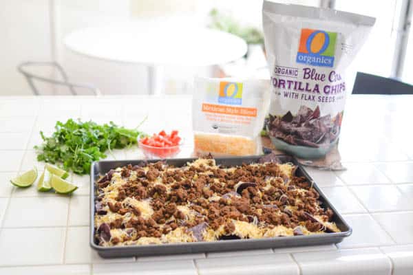 Chips and cheese with ground beef on top on a cookie sheet on a counter.