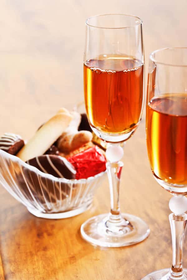 Glass of sherry on a table next to a bowl of nuts.