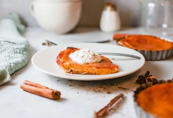 A slice of Pumpkin Pie with Fireball on a plate topped with whipped cream.