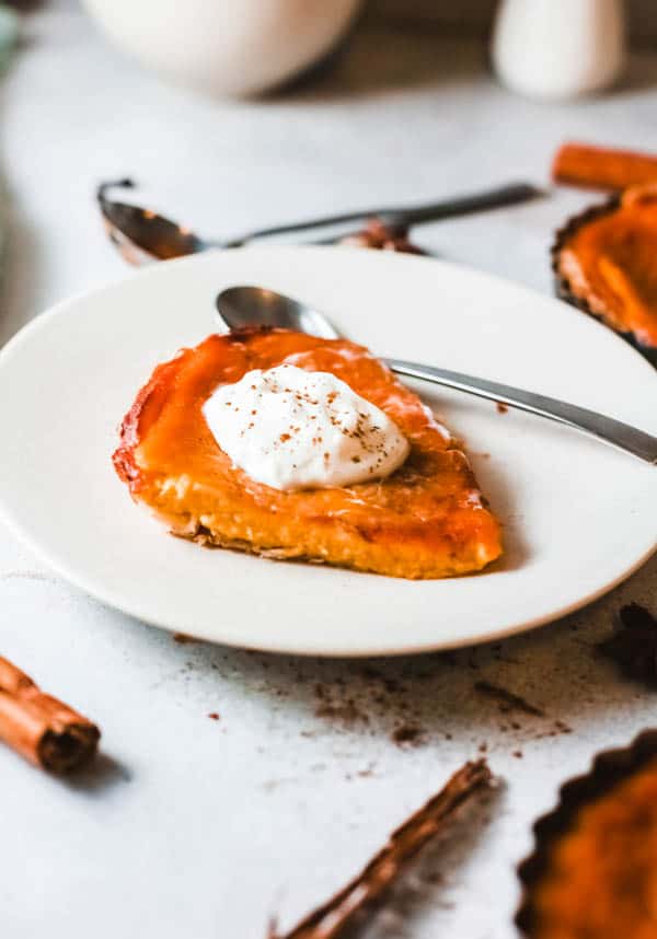 Slice of boozy Fireball Pumpkin Pie on a plate topped with whipped cream.