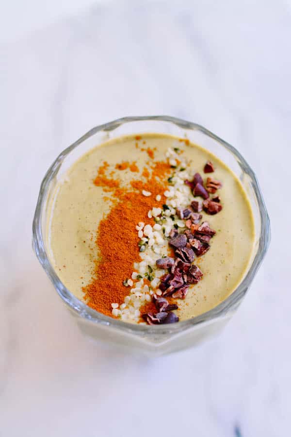 Overhead view of a banana avocado smoothie with cinnamon, hemp seeds and cocoa nibs.