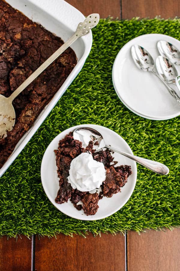 Overhead view of chocolate dump cake in a baking dish and some on a plate next to it.