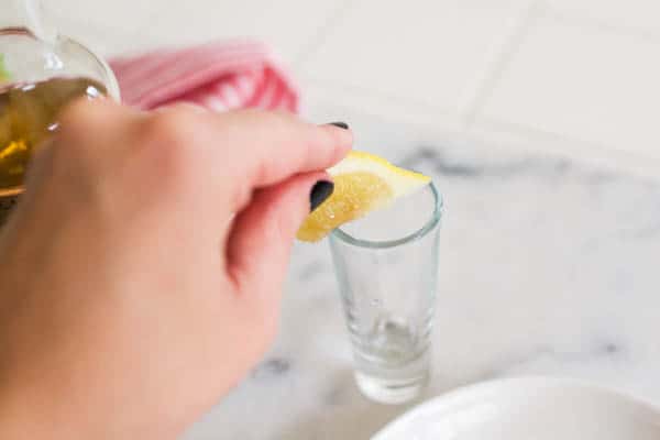 Rubbing a lemon on the rim of a shot glass.