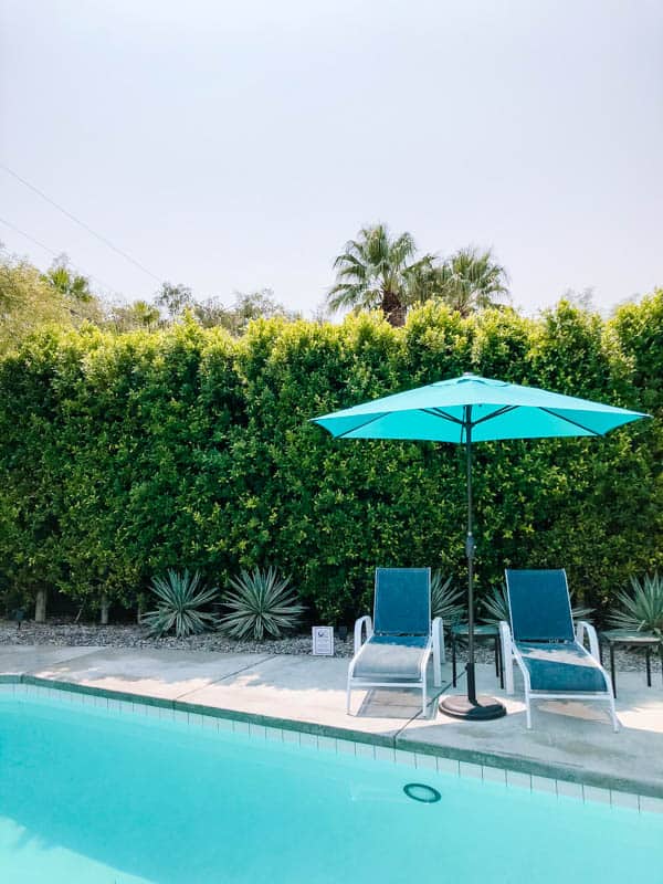 Lounge chairs and umbrella by a pool.