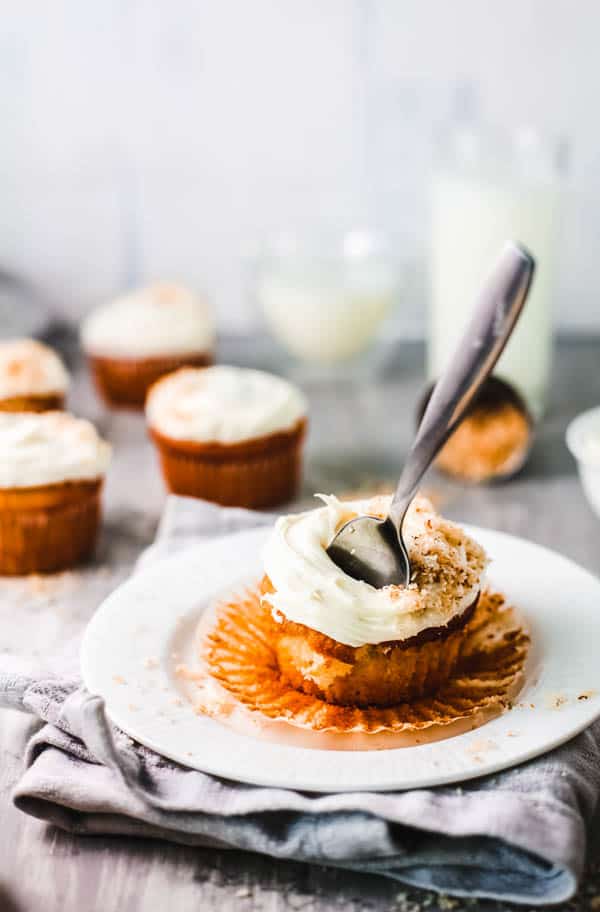 Coconut and rum infused cupcake on a dessert plate with a fork sticking out of it.