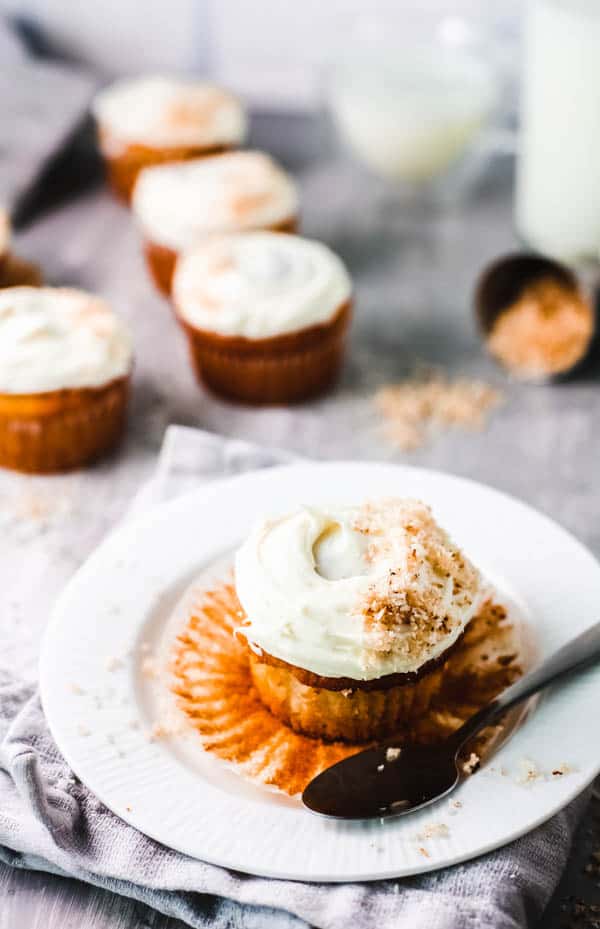 Frosted cupcake on a dessert plate on a table with other cupcakes sitting around it.