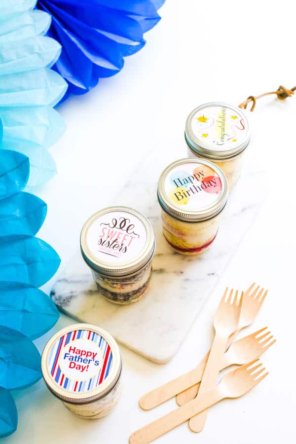 Overhead view of cupcakes in jars on a table next to wooden forks.