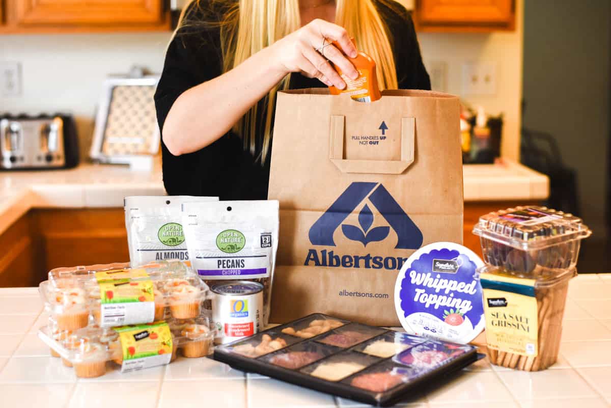 Woman unpacking groceries from a paper bag on the counter.