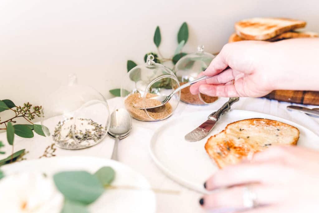 Woman spooning out some sugar out of a bowl.