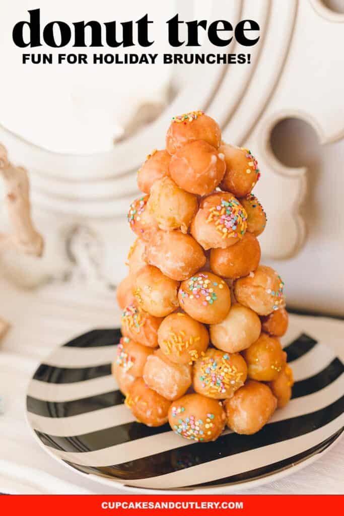 A donut hole tower on a black and white striped plate on a table.