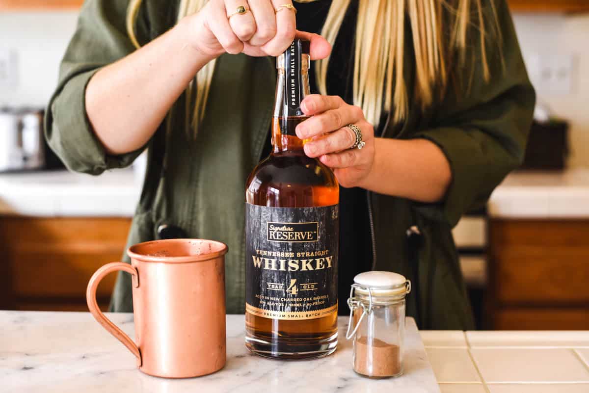 Woman opening a bottle of whiskey.