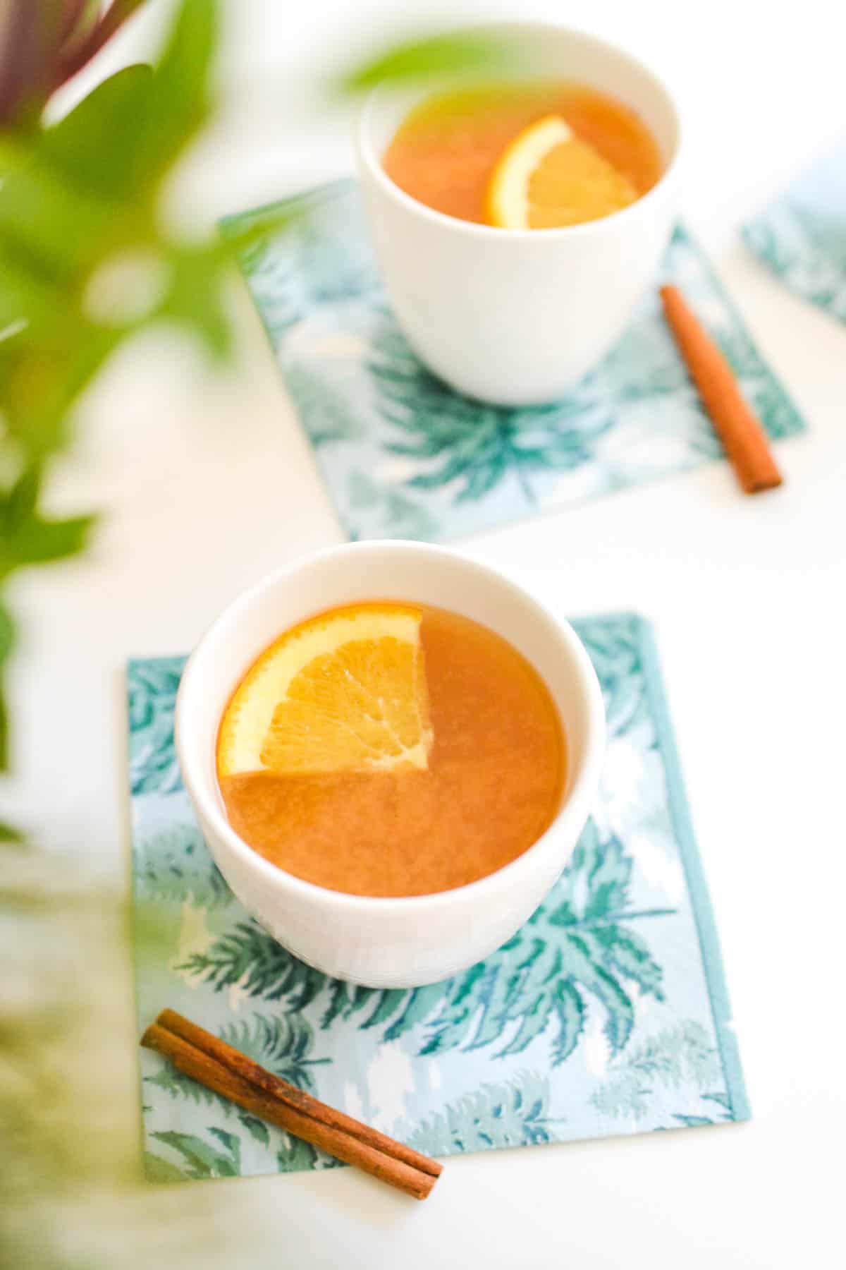 Close up shot of hot apple cider in small white mugs.