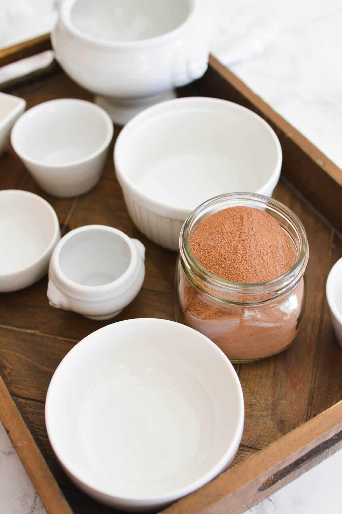 Hot cocoa in a mar on a tray next to some empty bowls.