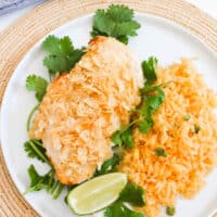 Close up of tortilla chip crusted chicken on a plate with rice.