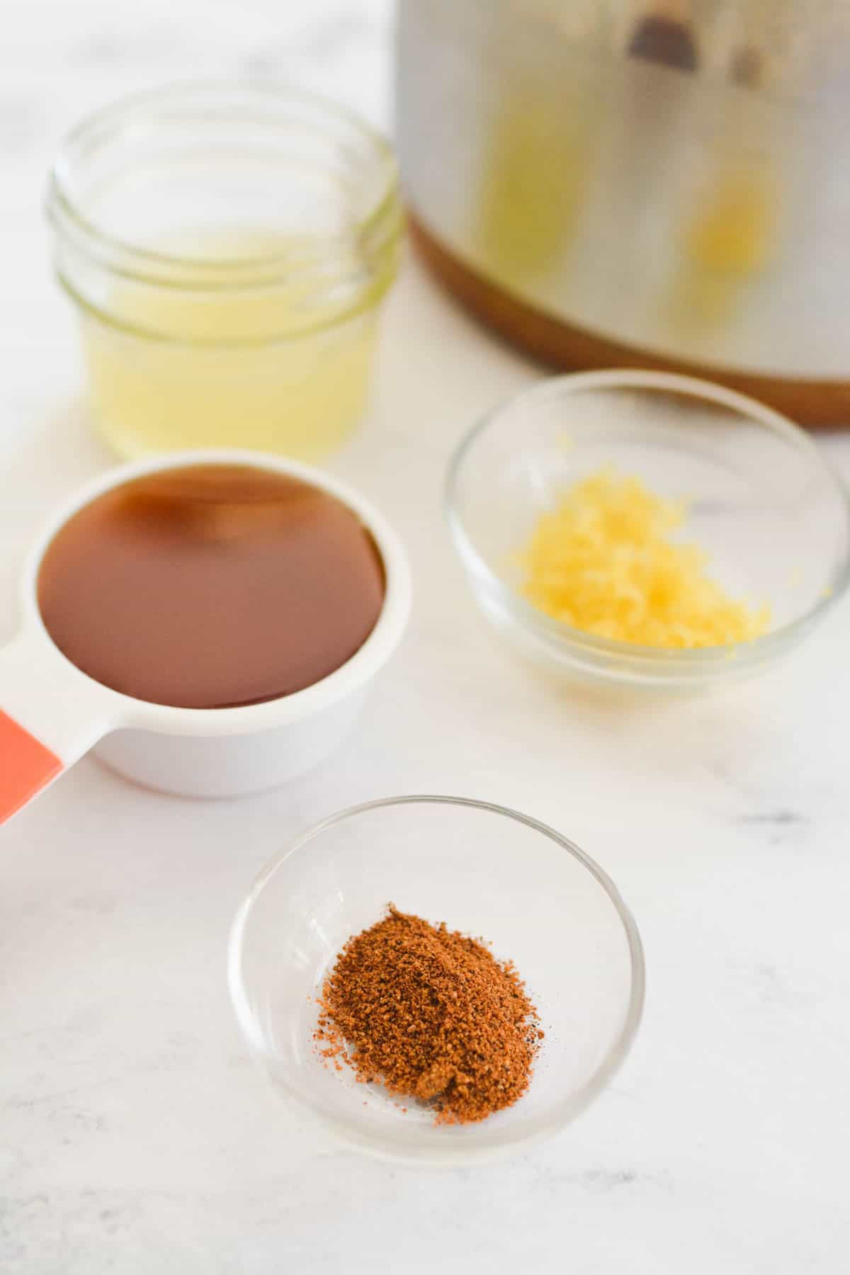 Spices and honey in small bowls next to a saucepan.