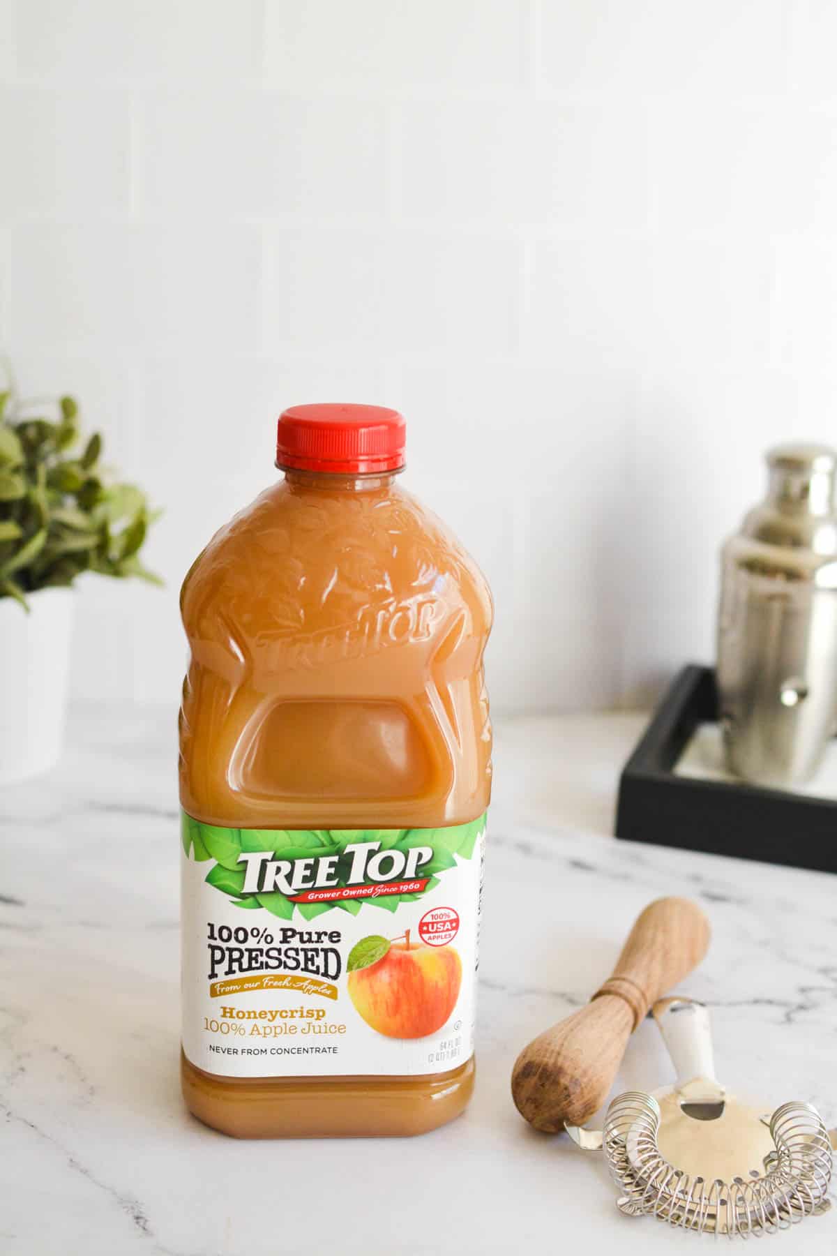 Bottle of apple juice on a table with bar tools.