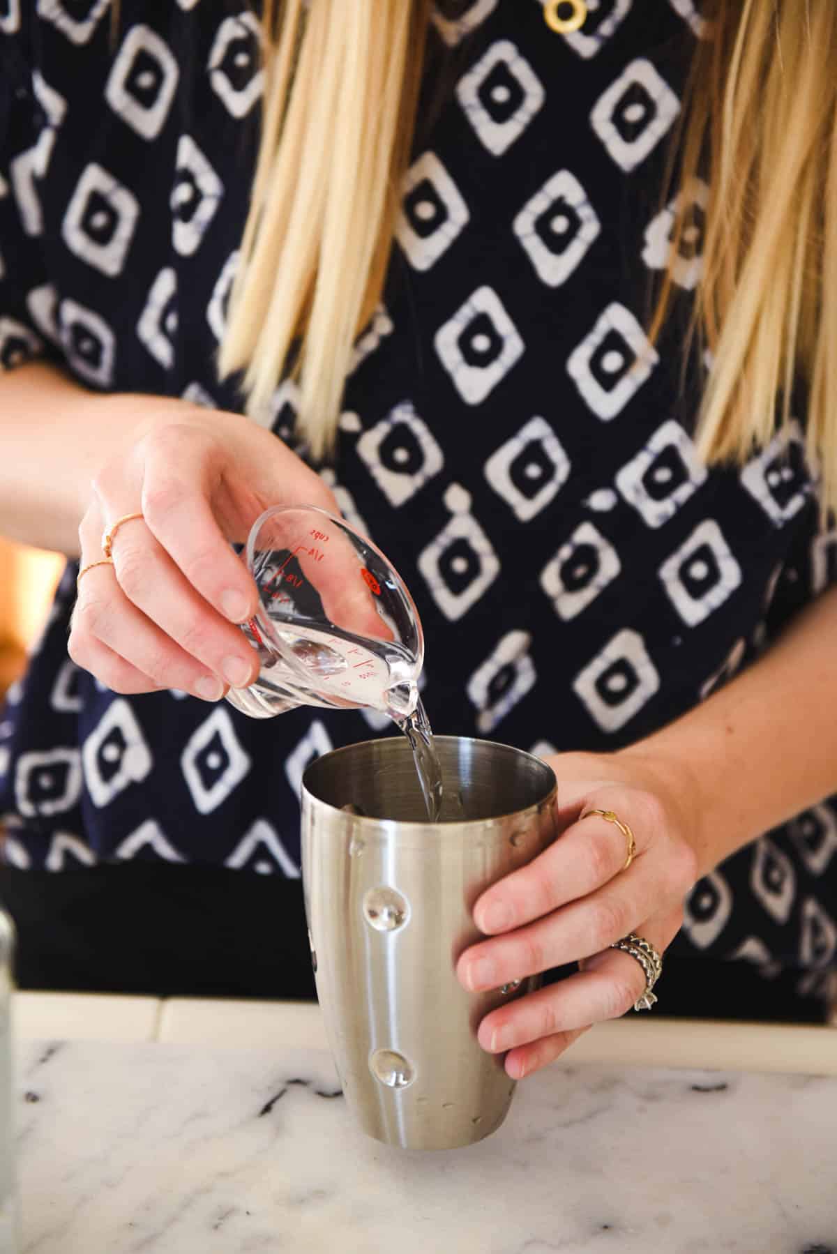 Woman adding margarita ingredients to the cocktail shaker.