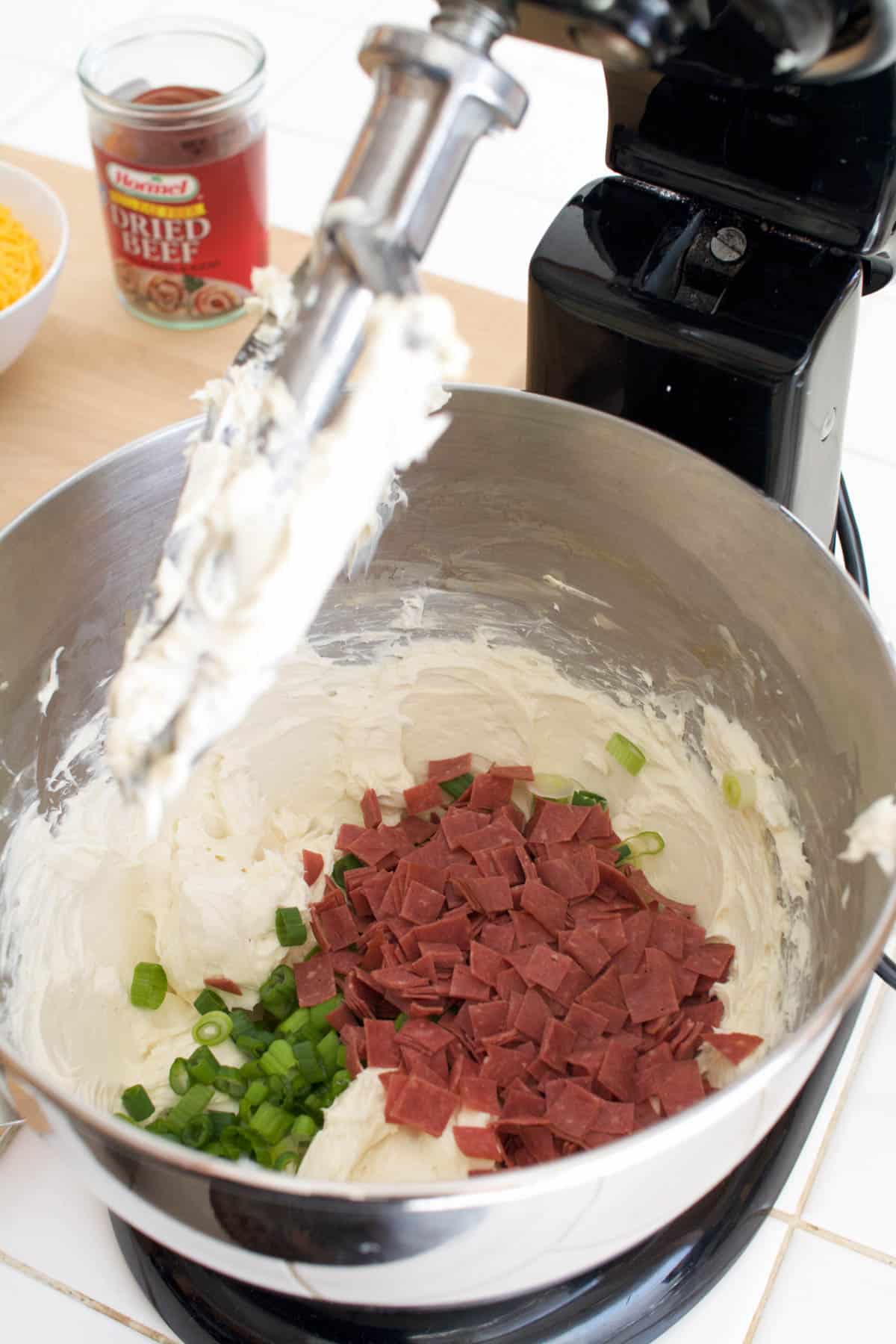 Stand mixer with cream cheese and dried beef with green onions for an appetizer.