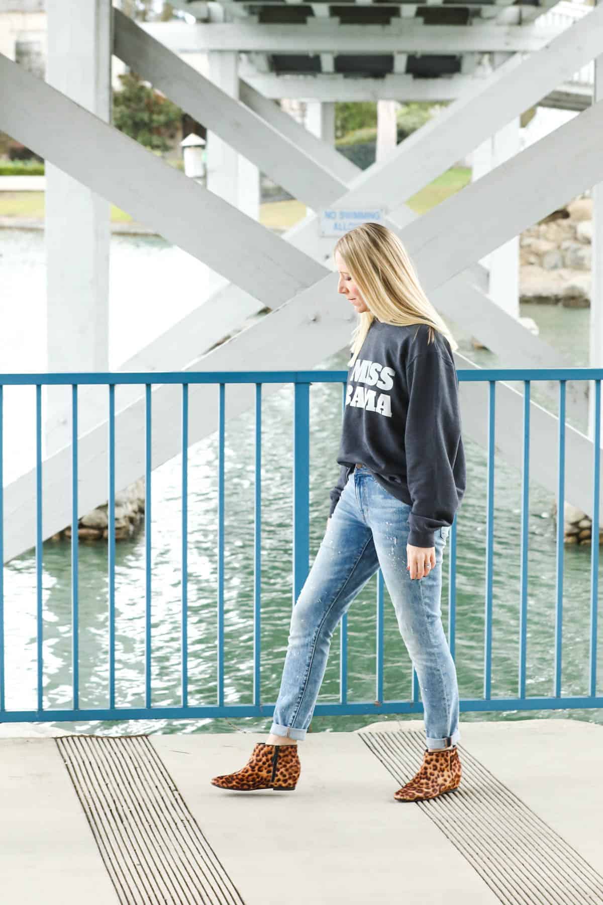 Woman walking wearing a sweatshirt.