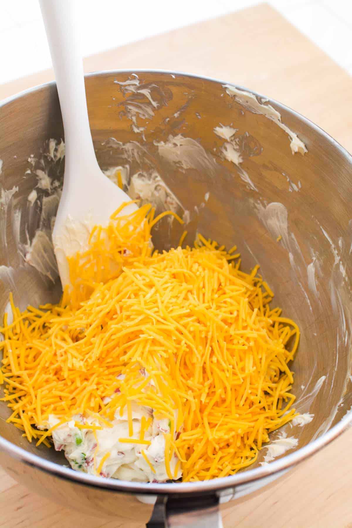 Overhead shot of a stand mixer bowl with cream cheese and cheese.