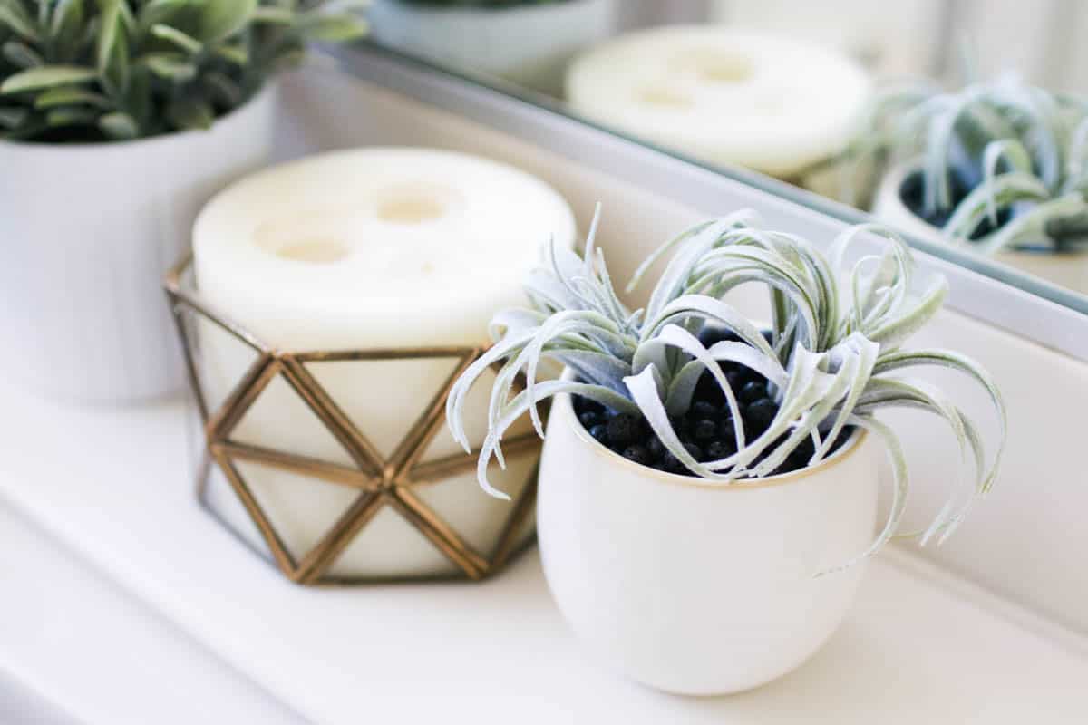 A diy essential oil diffuser with lava beads and a fake succulent next to a candle.