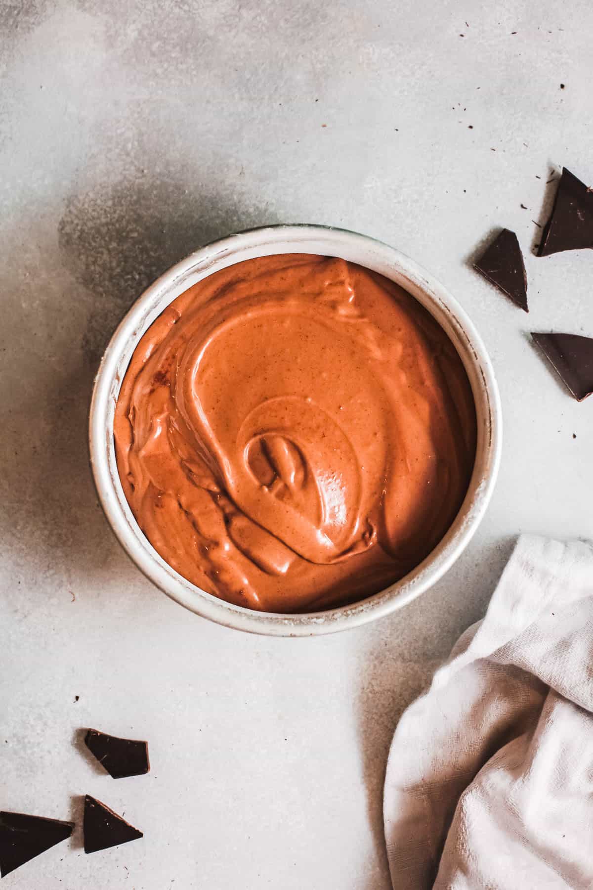 Raw chocolate cake batter in a 9" round cake pan on a counter. 