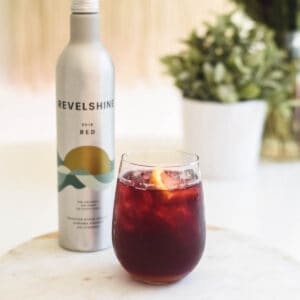 Close up of a Red Wine cocktail on a table next to a small aluminum bottle of wine.