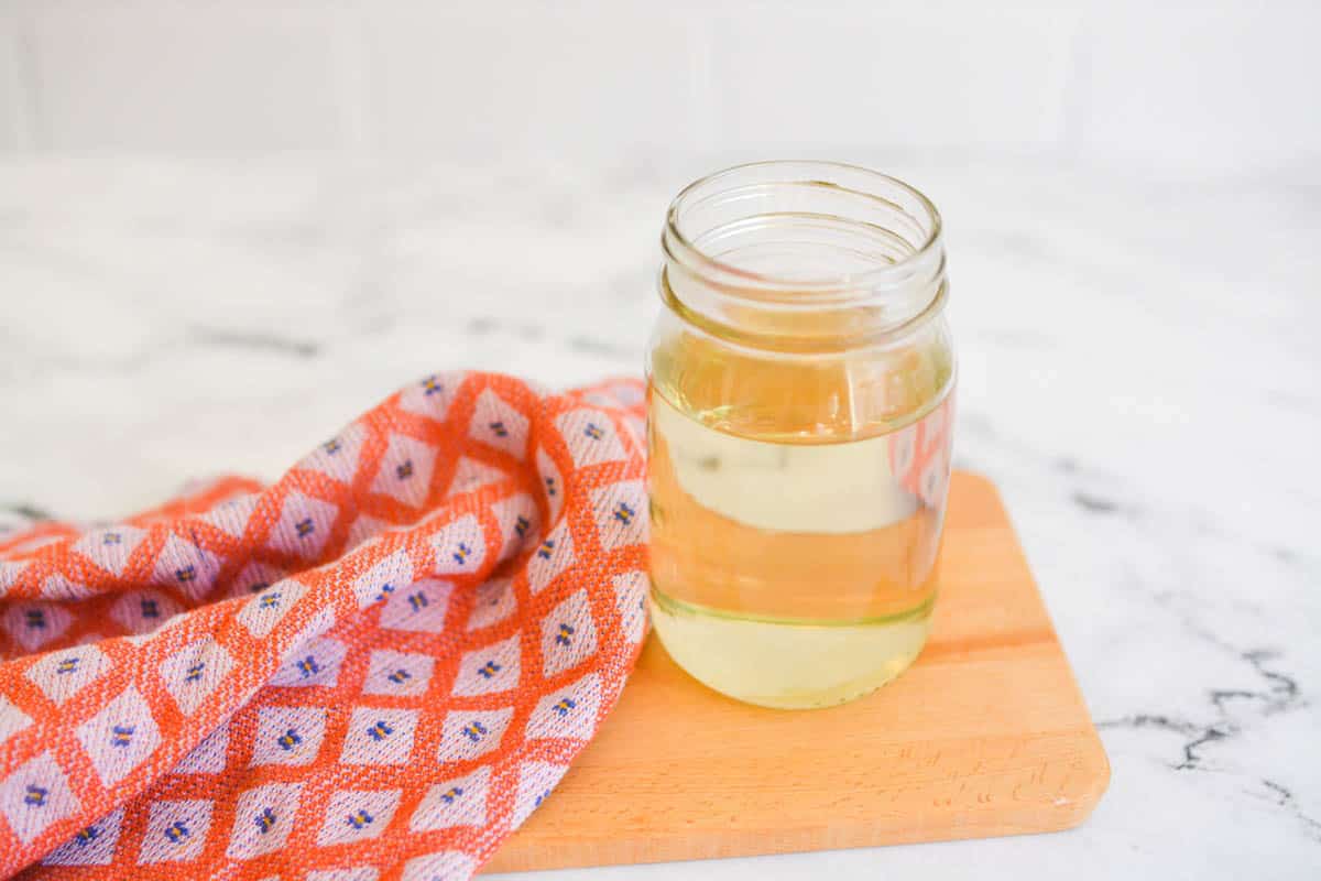 A jar on a cutting board holding simple syrup for cocktails.