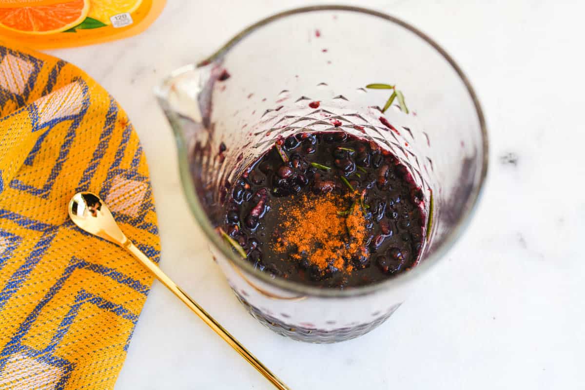 Overhead shot of cinnamon and smashed blackberries in a bar pitcher.