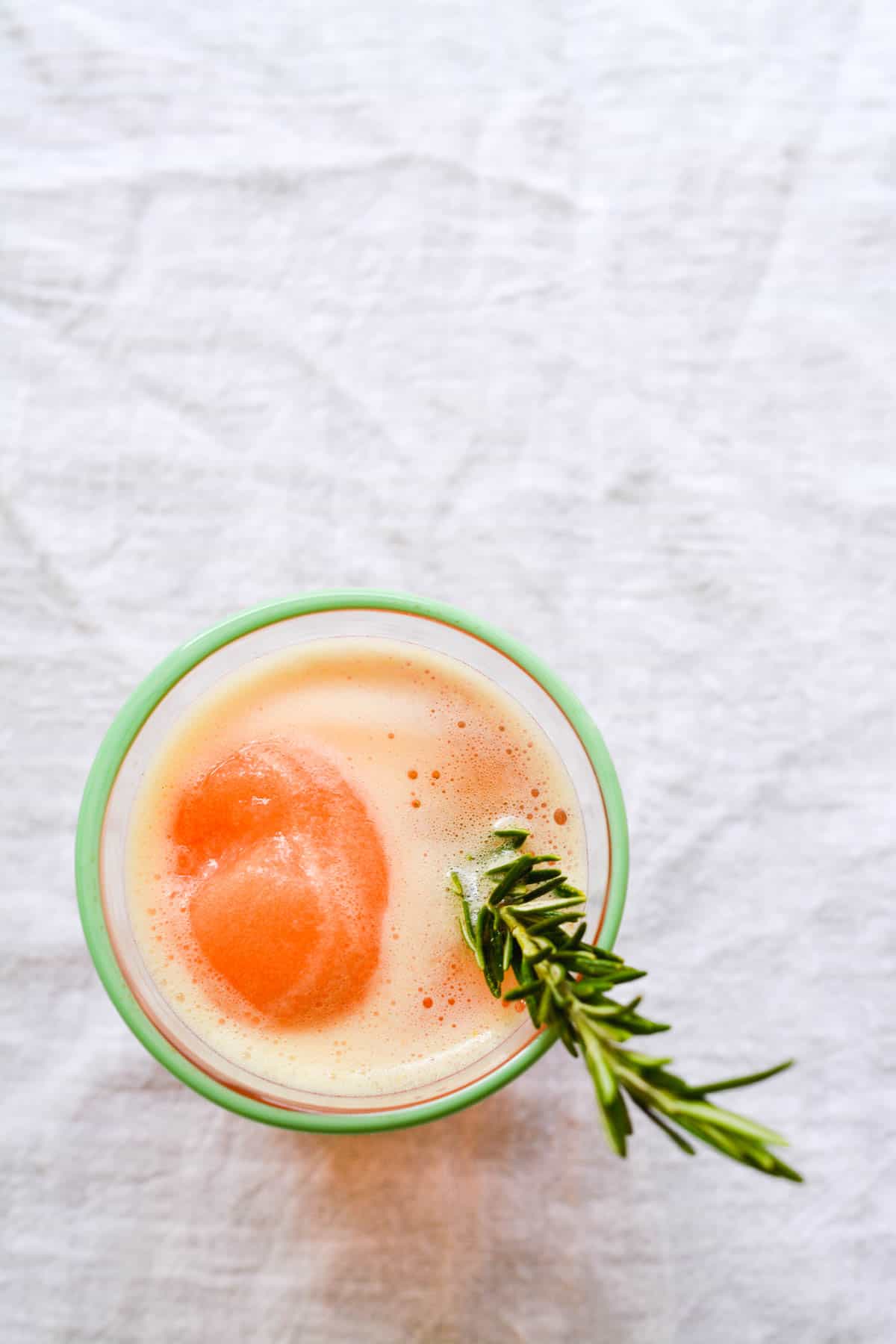 Top of a cocktail cup with a gin and tonic with blood orange sorbet and a rosemary garnish.