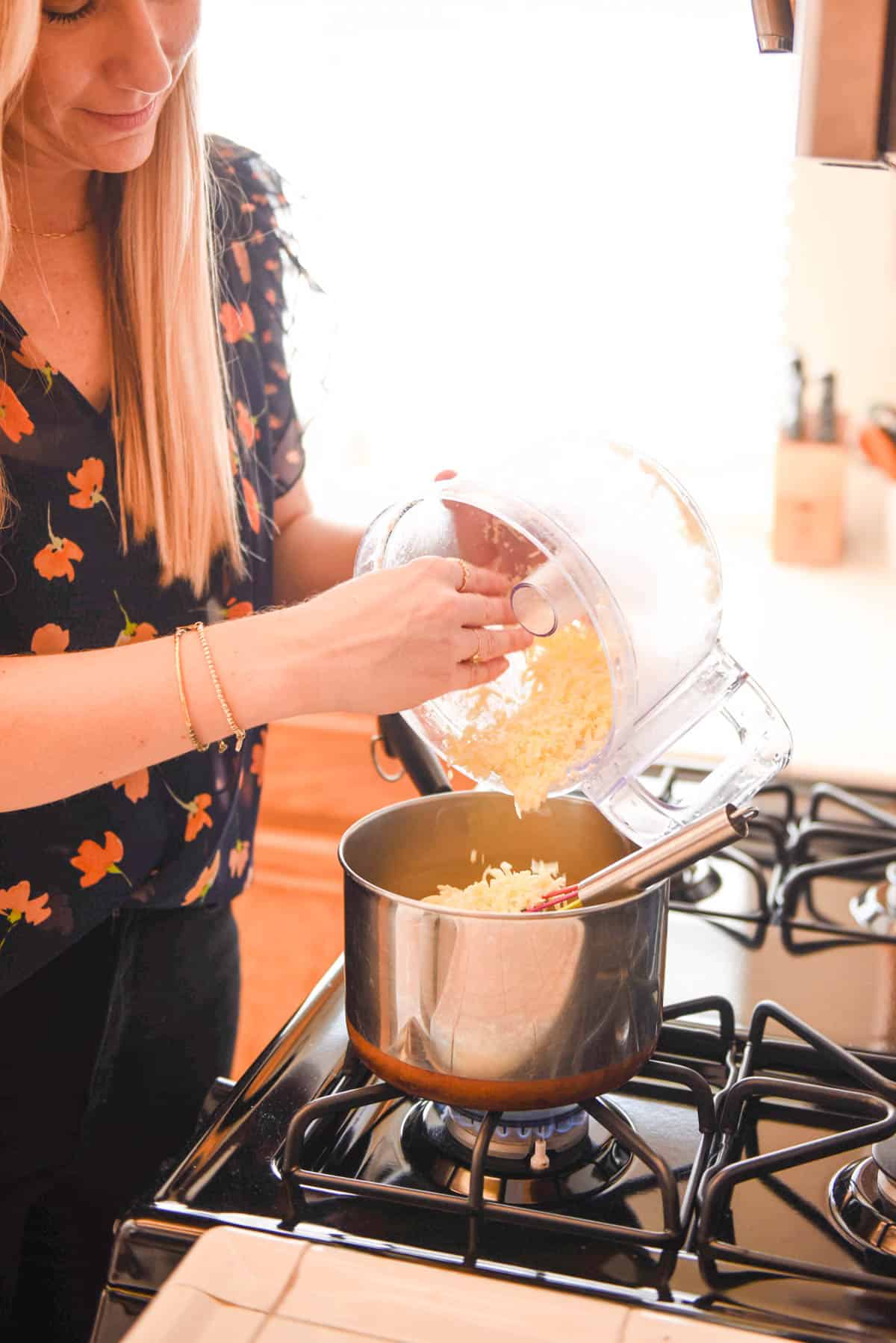Woman adding cheese to a saucepan.