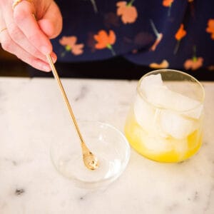 Hand mixing a clear liquid in a small glass bowl.