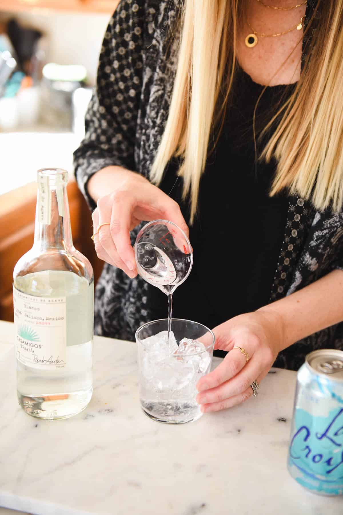 Woman adding tequila to a cocktail glass.